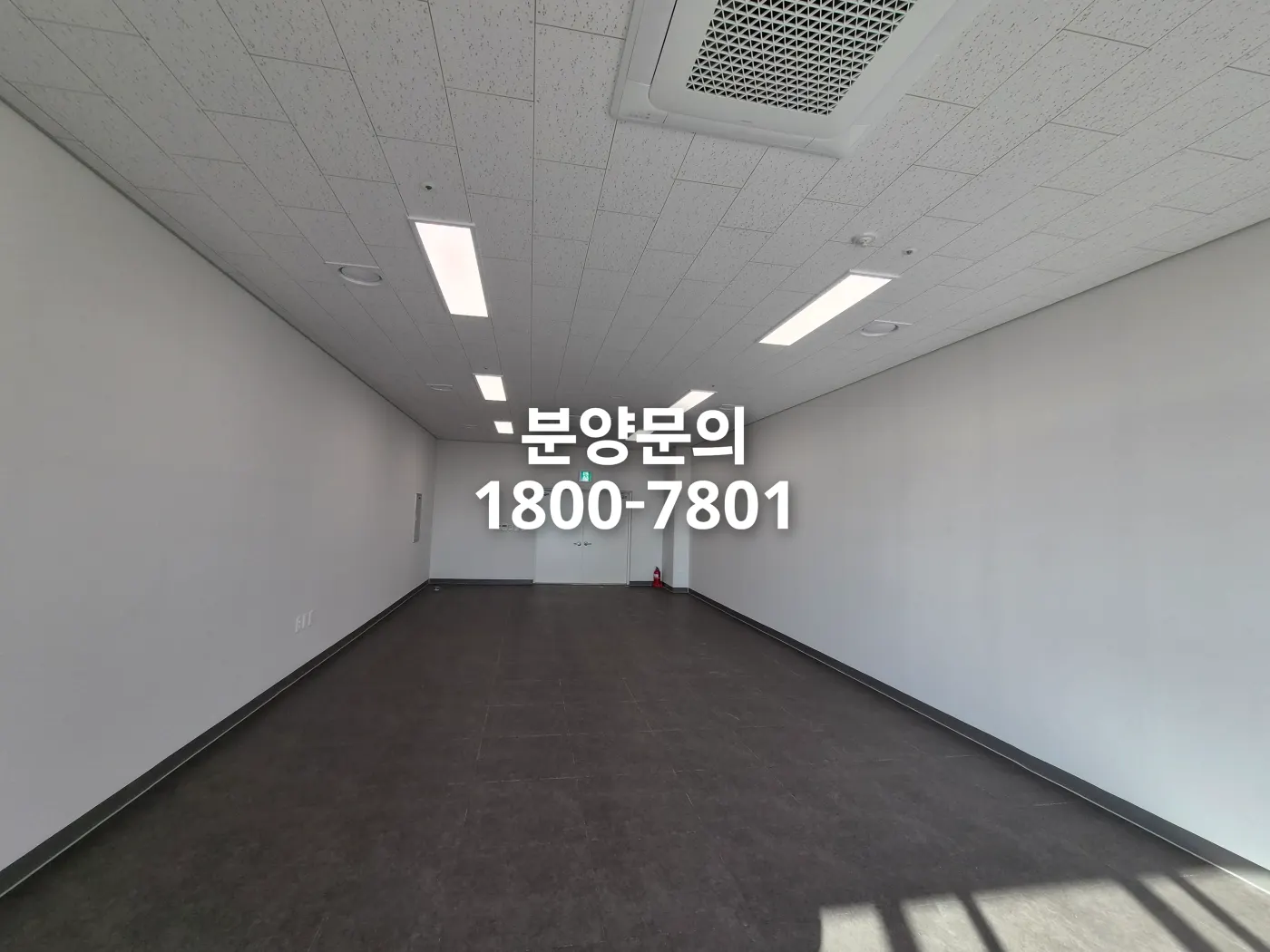 대전 플랫폼시티 넓은 업무 공실. 어두운 타일 바닥과 그리드 천장, 이중 출입문과 비상구 표시가 보이는 현장 사진